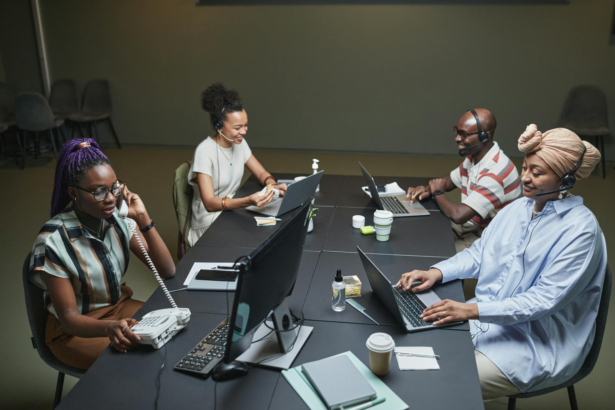 Diverse call center team working collaboratively with technology and headsets in a modern office setting.